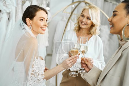 eine junge Braut im Brautkleid und ihre Mutter mittleren Alters, die Weingläser in der Hand hält und freudig lächelt.