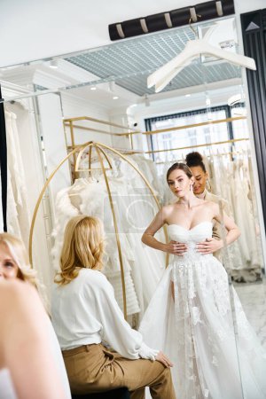 A young, beautiful bride in a white dress standing in front of a mirror, admiring her reflection in a wedding salon.