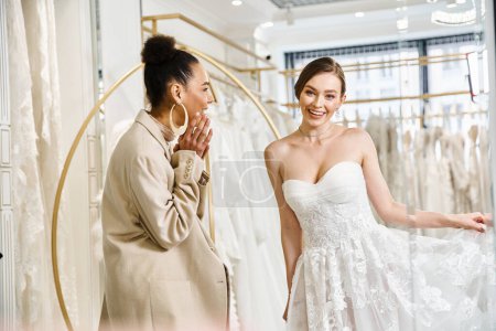 Téléchargez les photos : Une jeune femme brune se tient à côté d'une belle mariée dans une robe blanche dans un salon de mariage. - en image libre de droit