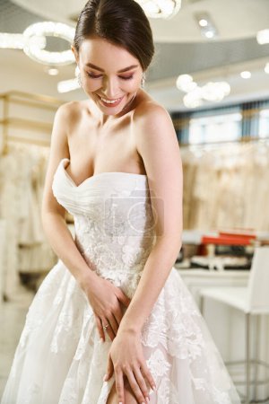 Eine junge brünette Braut lächelt glücklich in einem weißen Kleid in einem Hochzeitssalon.