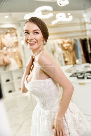 A beautiful, young brunette bride in a white dress striking a serene pose in a wedding salon.