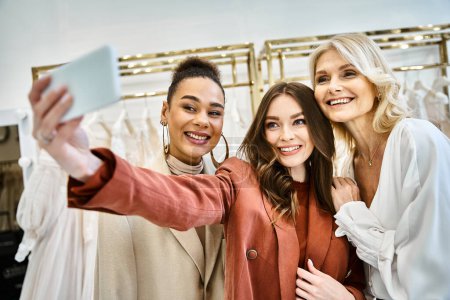 Foto de Dos mujeres jóvenes, una futura novia y su mejor amiga, posan mientras toman una selfie en una tienda de ropa de moda. - Imagen libre de derechos