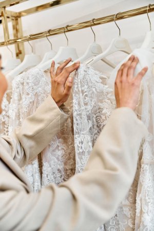 A young, beautiful bride tries on a stunning white wedding dress in a boutique.