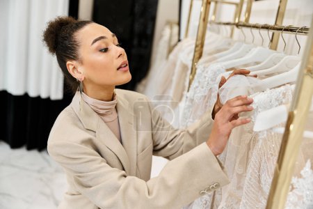 Eine junge, schöne Braut schaut sorgfältig durch eine Auswahl an Brautkleidern