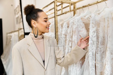 A young beautiful bride is carefully inspecting a rack filled with elegant wedding dresses