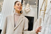 A young beautiful bride stands in front of a rack of dresses, carefully selecting her wedding gown Sweatshirt #698530372