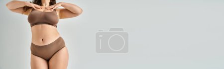 Foto de Estandarte de mujer con curvas en ropa interior tocando su escote con las manos sobre fondo gris - Imagen libre de derechos