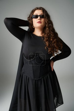 attractive plus size woman in sunglasses with hand on waist holding fur coat behind back