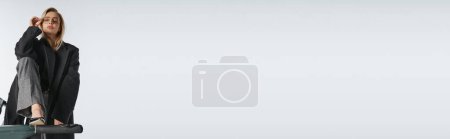 Téléchargez les photos : Séduisante femme gracieuse dans des lunettes et manteau posant sur tapis roulant et regardant la caméra, bannière - en image libre de droit