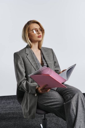 Foto de Debonair mujer de negocios de moda en traje gris inteligente con gafas que trabajan con su papeleo - Imagen libre de derechos