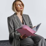 debonair fashionable businesswoman in smart gray suit with glasses working with her paperwork
