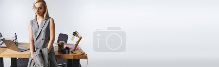 Foto de Elegante mujer de negocios de buen aspecto en traje gris sofisticado con cabello rubio mirando hacia otro lado, pancarta - Imagen libre de derechos