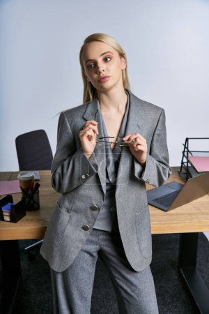 Foto de Mujer de negocios de buen aspecto de moda en traje gris sofisticado con cabello rubio mirando hacia otro lado - Imagen libre de derechos