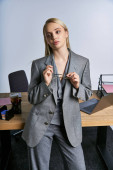 fashionable good looking businesswoman in sophisticated gray suit with blonde hair looking away puzzle #698846144
