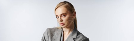 Photo for Hard working businesswoman in sophisticated gray suit looking at camera on gray backdrop, banner - Royalty Free Image