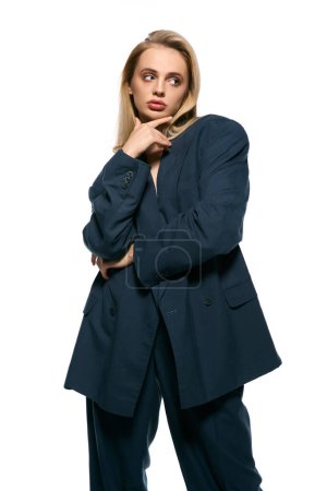 Photo for Beautiful sexy woman with blonde hair in black unbuttoned suit on white backdrop and looking away - Royalty Free Image