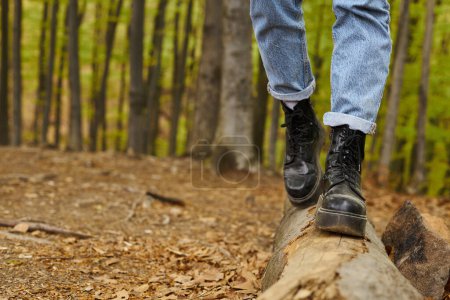 Cropped photo of female legs in hiking boots making a step on a wood in forest scenery