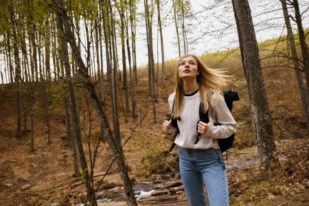 Photo for Young woman with backpack walking in the forest, hiking and going camping in nature environment - Royalty Free Image