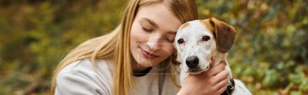 Téléchargez les photos : Femme souriante étreignant doucement son compagnon de chien avec les yeux fermés pendant le voyage de sac à dos, bannière - en image libre de droit