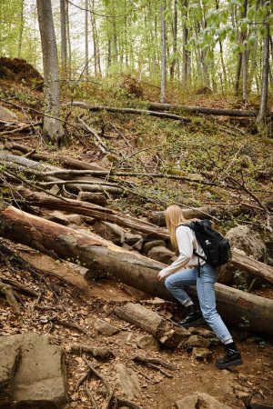 Woman with backpack hiking on footpath in autumn forest. Solo female tourist outdoors