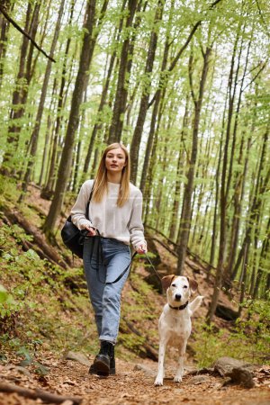 Mujer alegre paseando a su perro mascota mientras tiene viaje de mochilero con compañero
