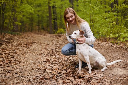 Glückliches Mädchen, das mit seinem Haustier interagiert und auf Hundewanderrast mit Waldblick schaut