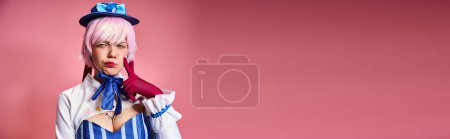 Attraktive Cosplayerin mit roten Handschuhen und blauer Mütze posiert emotional auf rosa Hintergrund, Banner