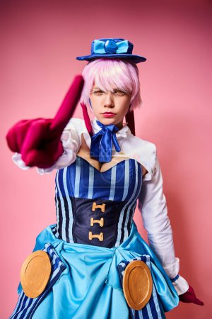 attractive female cosplayer in vibrant dress with blue hat pointing at camera on pink backdrop Stickers 699817060