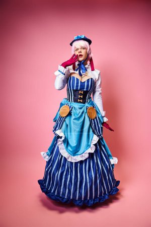 shocked pretty woman with blue hat and red gloves cosplaying anime character and looking at camera