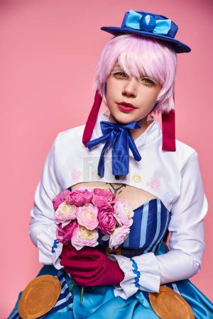 Foto de Cute jolly female cosplayer in bright anime costume holding pink flowers and looking at camera - Imagen libre de derechos