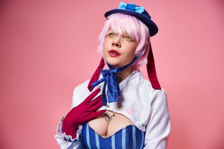 appealing fashionable woman cosplaying cute anime character and looking away on pink backdrop