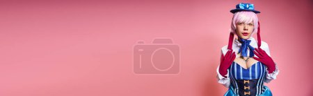alluring female cosplayer in blue hat and vivid dress looking at camera on pink backdrop, banner