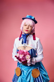 alluring cute female cosplayer in vibrant costume holding pink flowers and looking at camera magic mug #699818034