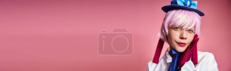 Téléchargez les photos : Attrayant cosplayer chic en chapeau bleu et robe vive regardant la caméra sur fond rose, bannière - en image libre de droit