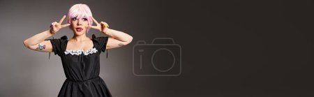 Photo for Alluring female cosplayer showing peace gesture and sticking out her tongue and looking away, banner - Royalty Free Image