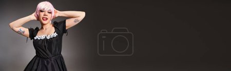 Téléchargez les photos : Joyeux cosplayer en costume de bonne avec les cheveux roses collant sa langue et regardant la caméra, bannière - en image libre de droit