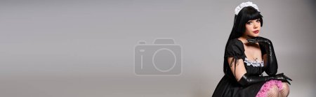 Photo for Sexy female cosplayer in tempting maid costume looking at camera on gray background, banner - Royalty Free Image