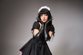 charming sexy female cosplayer in tempting maid costume looking at camera on gray background Poster #699820040
