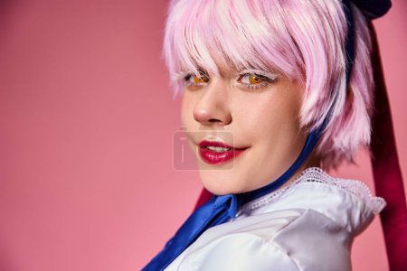 cheerful attractive female cosplayer in vibrant attire smiling at camera on pink background