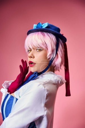 appealing woman cosplaying anime character with blue hat and red gloves and looking at camera