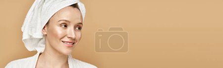 Téléchargez les photos : Une belle femme à la beauté et la grâce naturelles, pose en toute confiance avec une serviette enroulée autour de sa tête. - en image libre de droit