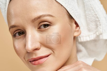 Una mujer atractiva con belleza natural posa graciosamente, llevando un turbante de toalla en la cabeza.