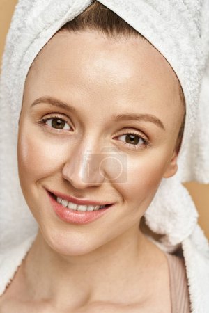 Foto de Una mujer impresionante con belleza natural posa elegantemente con una toalla envuelta alrededor de su cabeza. - Imagen libre de derechos