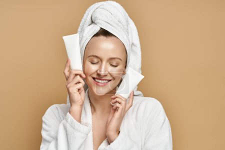 Foto de Una mujer en un albornoz misteriosamente sosteniendo una crema sobre su cara, exudando elegancia y encanto. - Imagen libre de derechos