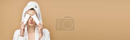 Photo for A woman in a bathrobe gently covers her face with a towel, revealing her natural beauty in an artistic pose. - Royalty Free Image