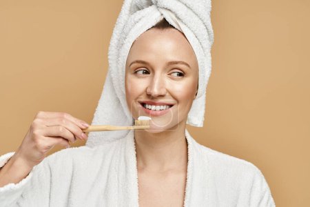 An attractive woman with a towel on her head is brushing her teeth in a daily morning routine.