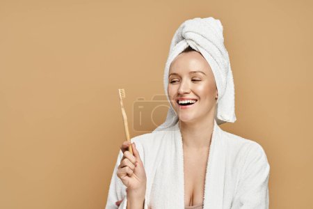 Pełna wdzięku kobieta z ręcznikiem owiniętym wokół głowy trzymająca szczoteczkę do zębów.