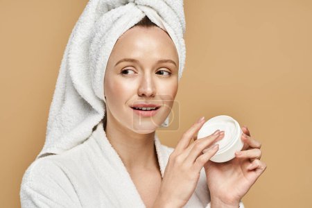 Una mujer de belleza natural sostiene un frasco de crema con una toalla en la cabeza.