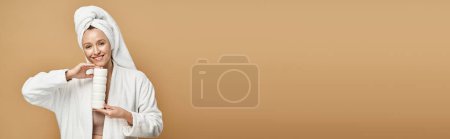 Photo for A beautiful woman in a white robe poses gracefully with a white cream. - Royalty Free Image