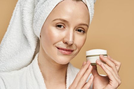 Photo for A woman with a towel on her head holds a jar of cream, embracing self-care and natural beauty. - Royalty Free Image
